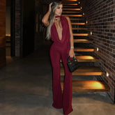 Woman in a burgundy jumpsuit standing on a staircase with brick walls.
